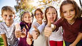 kids smiling in a row with thumbs up