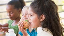 girl smiling while eating sandwich