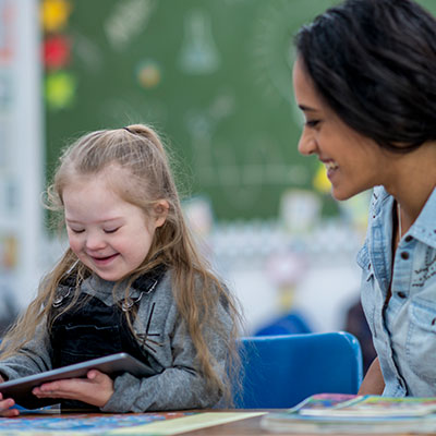 Girl with special needs on iPad with teacher